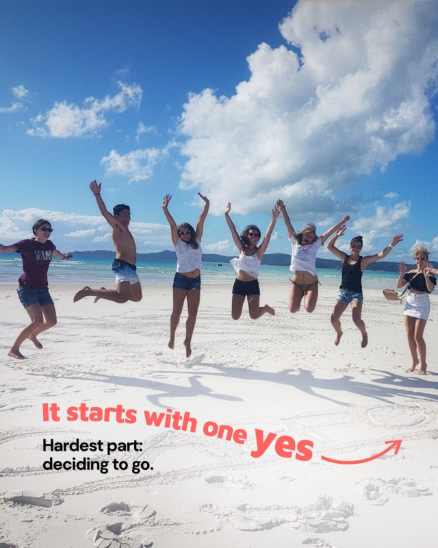 Group of travellers jumping in the air on a white sand beach in Australia
